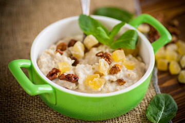 cooked boiled sweet oatmeal with nuts and candied fruits in a bowl