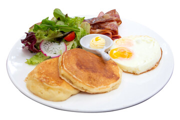 Full American Breakfast Sunny side fried egg, roasted bacon, pancakes, salad and butter served on white plate isolated on white background with clipping path