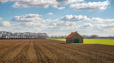 Small barn in a plowed field. It's in a sunny day at the beginning of the Dutch spring season.