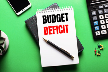 On a green background - a telephone, a calculator and a diary with the inscription BUDGET DEFICIT