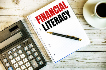 FINANCIAL LITERACY written on white paper near coffee and calculator on a light wooden table. Business concept