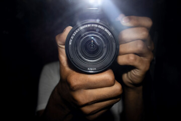 A reflection in a mirror of a man with camera in hand looking through the camera lens. - obrazy, fototapety, plakaty