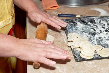 Hand holds a wooden rolling pin soiled in flour