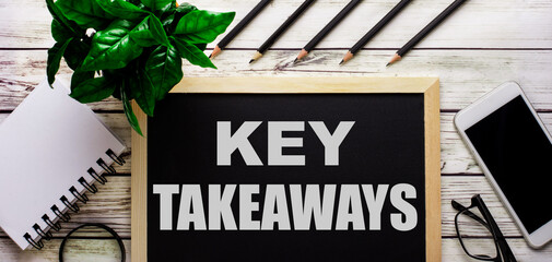 KEY TAKEAWAYS is written in white on a black board next to a phone, notepad, glasses, pencils and a...