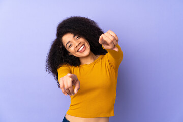 Young african american woman isolated on purple background pointing front with happy expression