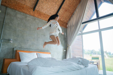 attractive asian woman jumping on bed in the morning, in the morning, She felt very refreshed,...