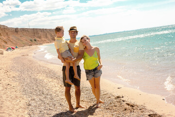 Fototapeta premium Active family, mother, father and son resting in the beach on vacation. people enjoy the sea, sand and healthy.