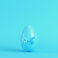 Easter egg with bow on bright blue background in pastel colors