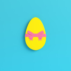 Yellow easter egg with bow on bright blue background in pastel colors