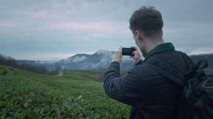 Photographer shots beautiful sunset with phone on the tea plantation