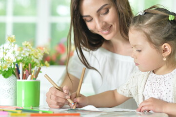 cute girl with mother drawing at the table