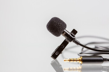 Small lavalier microphone or lapel mic with clip on white background.