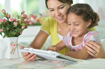 happy mother and daughter using tablet together at home