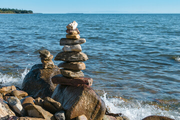 Pyramids of stacked stones on boulder on the inshore waves of Lake Baikal, scenic seascape, balance and harmony concept
