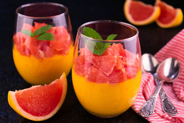 Cream Kurd from grafruit in glasses on a black background.
Close-up.