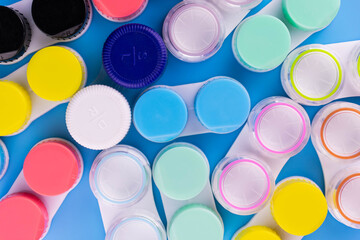 A lot of containers for contact lenses on a blue background. Flat lay.