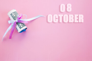 calendar date on pink background with rolled up dollar bills pinned by pink and blue ribbon with copy space. October 8 is the eighth day of the month