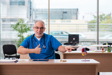 Old male doctor cardiologist working in the clinic