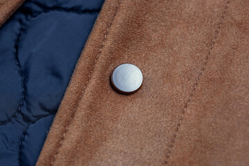 Close-up of a button-down button on a faux suede jacket