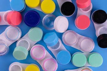 A lot of containers for contact lenses on a blue background. Flat lay.