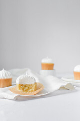 Vanilla cupcake with a meringue frosting, cupcake with a bite taken out it, white frosting on cake