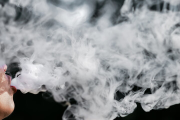 Close-up of a man spewing cigarette smoke from his mouth, black background, and space for text.