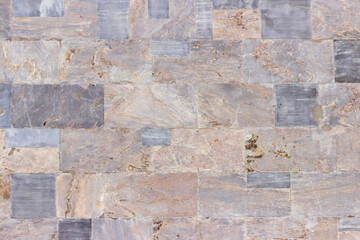 The surface of the wall of the building, made of hewn marble blocks of different sizes and colors.