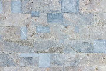 The surface of the wall of the building, made of hewn marble blocks of different sizes and colors.