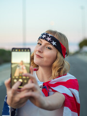 Mujer joven rubia con ojos azules haciéndose un selfie el Día de la Independencia de los Estados Unidos