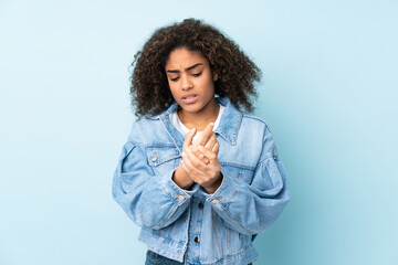Young African American woman isolated on blue background suffering from pain in hands