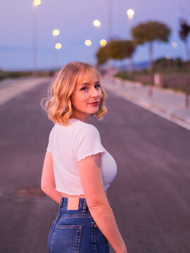 chica rubia en una carretera con luces de fondo