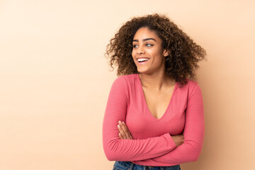 Young African American woman isolated on beige background happy and smiling