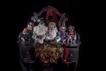  Scary dead dolls sit on the chest of drawers near the mirror. Zombie dolls. Dark horror room.