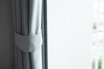 Detail of window grey curtain with tieback in the living room or bedroom.