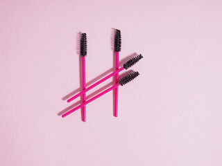 Pink eyelash brushes on a pink background with copyspace