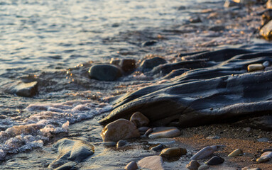 pebble stones on the sea beach, the rolling waves of the sea with foam