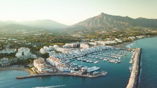 4K aerial perspective of luxury Puerto Banus Bay, in exclusive area of Marbella. Famous location for expensive lifestyle , luxury yacht, exclusive brands shopping area. Camera tilt down over yachts