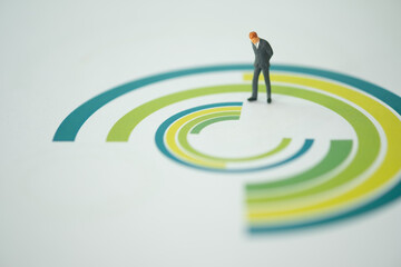 Miniature businessman standing on the circle chart paper and stance with thinking