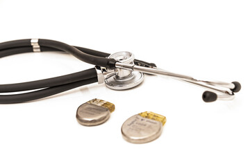 TWO PACEMAKER BATTERIES SURROUNDED BY A STETHOSCOPE WHITE BACKGROUND