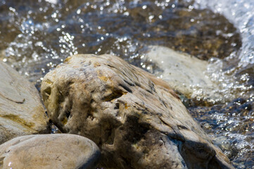 pebble stones on the sea beach, the rolling waves of the sea with foam