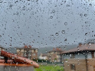 Detalle de gotas en ventana con paisaje lluvioso desenfocado en el fondo