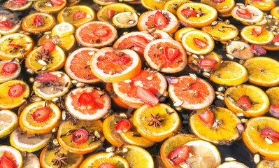 Yellow and red slices of fruit are cooked in a large vat of mulled wine.