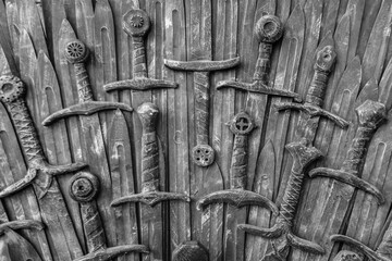 Lots of swords on a wooden surface. A wooden wall of swords
