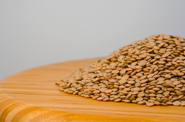 Brown lentils on white background. Raw lentils on wooden tray.   Copy text.