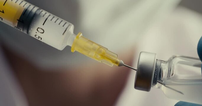 Doctor filling syringe with vaccine
