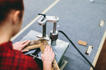 Woman worker sticking together a wooden frame with glue.