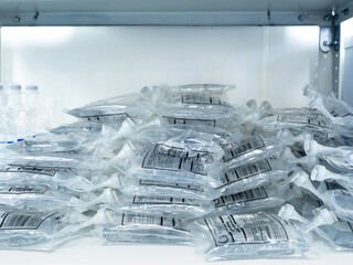A large pile of intravenous saline bags in a hospital on a rack. The inscription on the package in Russian indicates the instructions for using the solution.