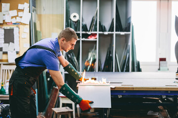 Glazier worker cutting glass with fire in a workshop