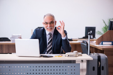 Old male employee preparing for travel in the office