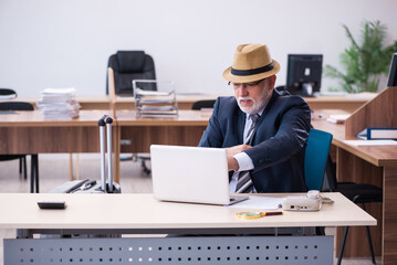 Old male employee preparing for travel in the office